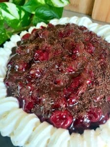 Chocolate cake filled with cherries and garnished with whipped cream